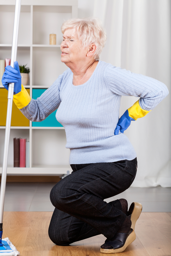 Woman experiencing bursitis hip pain while cleaning floor