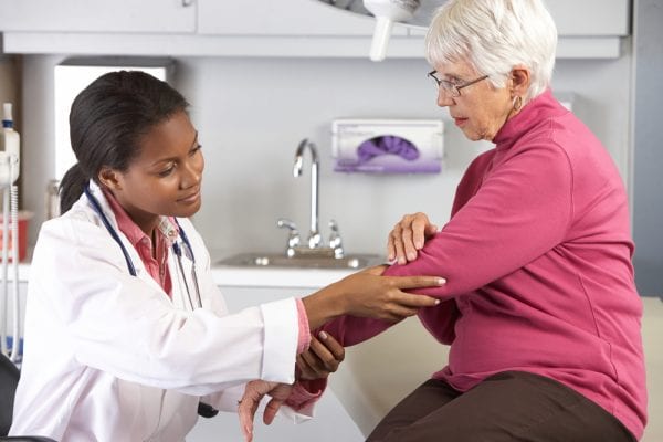 Female doctor examining elderly woman for signs of arthritis